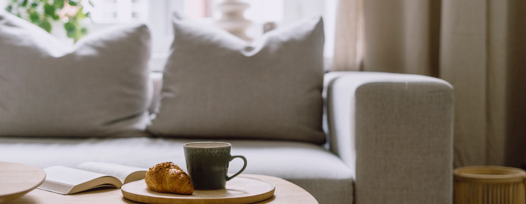 Comfy living room with white couch with coffee and pastry on coffee table